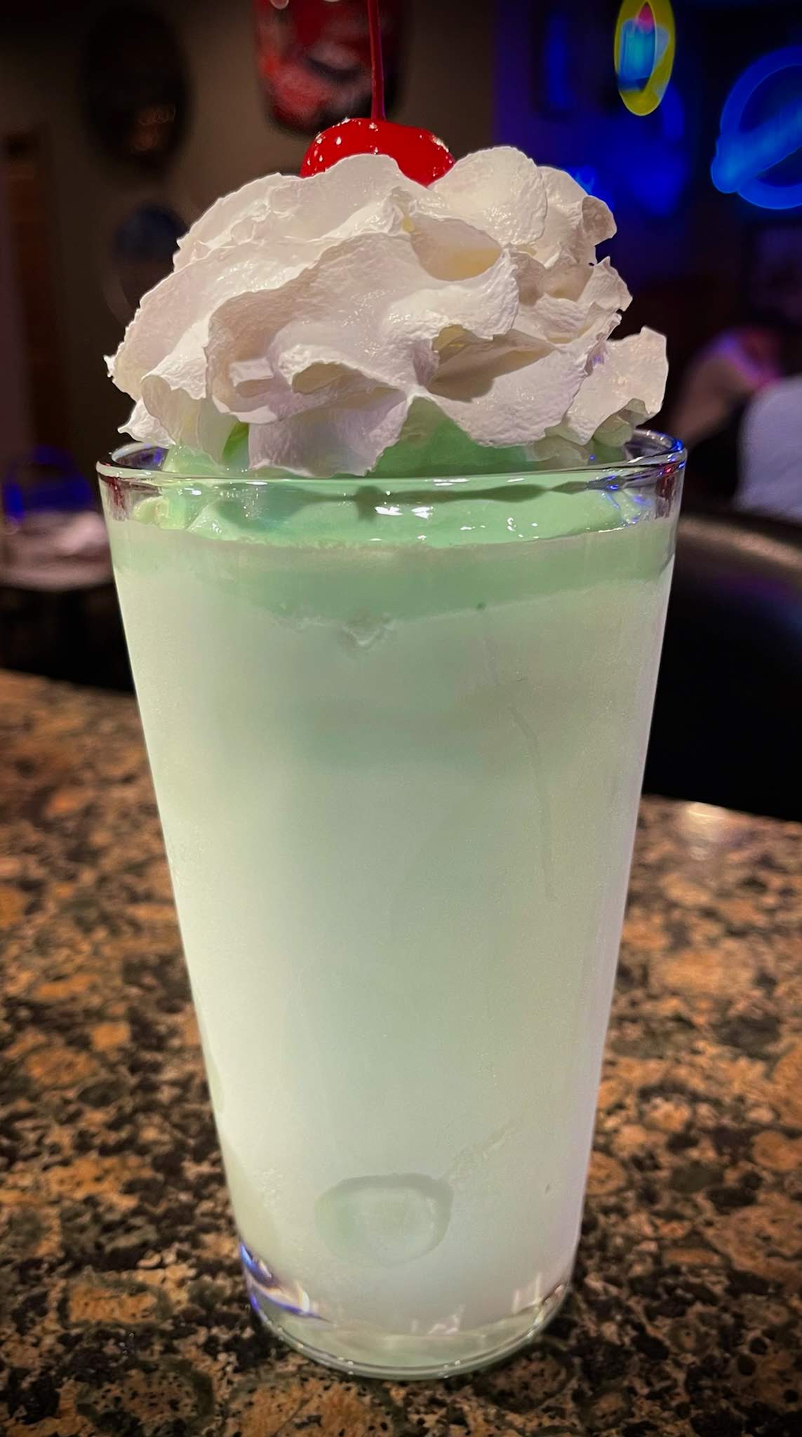 A tall ice cream cocktail topped with whipped cream and a cherry