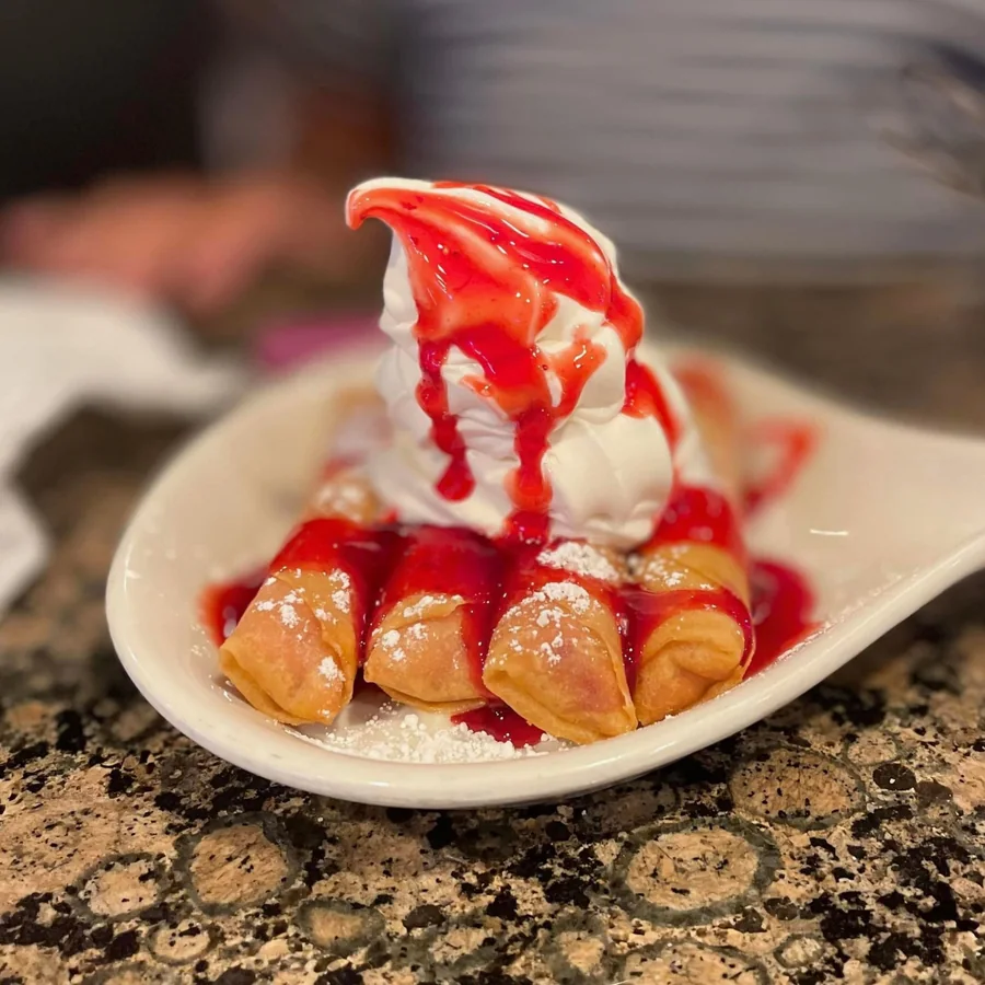 Strawberry dessert egg rolls at Sally's, dusted with powdered sugar and topped with soft serve and strawberry sauce