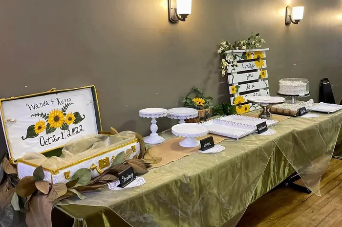 A dessert table laid out with cake stands and a hand-lettered sign