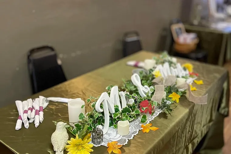 A head table decorated with a Mr and Mrs sign, candles and flowers