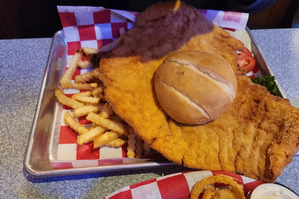 The Woody, a half pound breaded pork tenderloin hanging well over the bun, served with fries